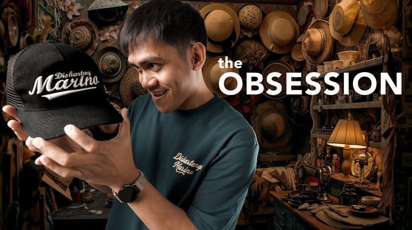 A man holding a Diskarteng Marino cap in a hat-filled studio.